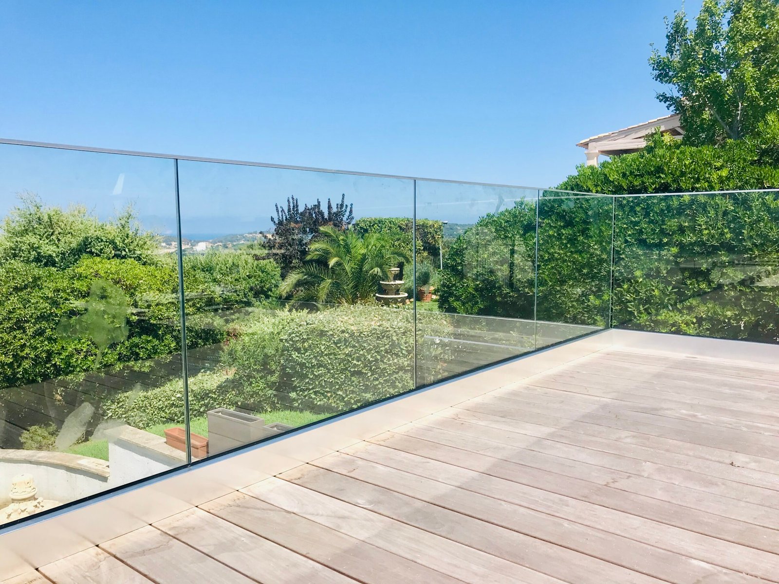 Protection de terasse posée sur lames bois dans un jardin arboré avec vue mer