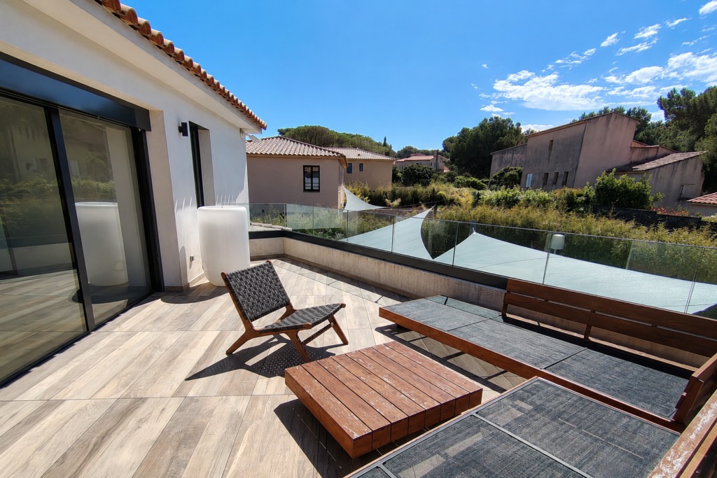 Garde-corps verre posé sur un muret pour protéger une jolie terrasse dalle sur plot avec bain de soleil